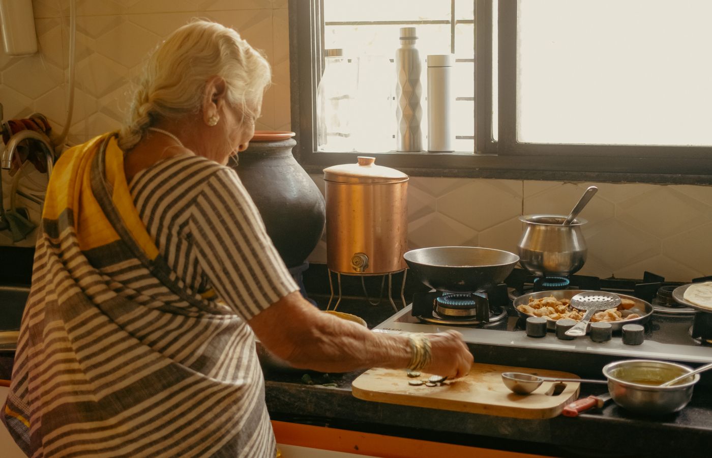 An older woman preparing a meal in her sunlit kitchen