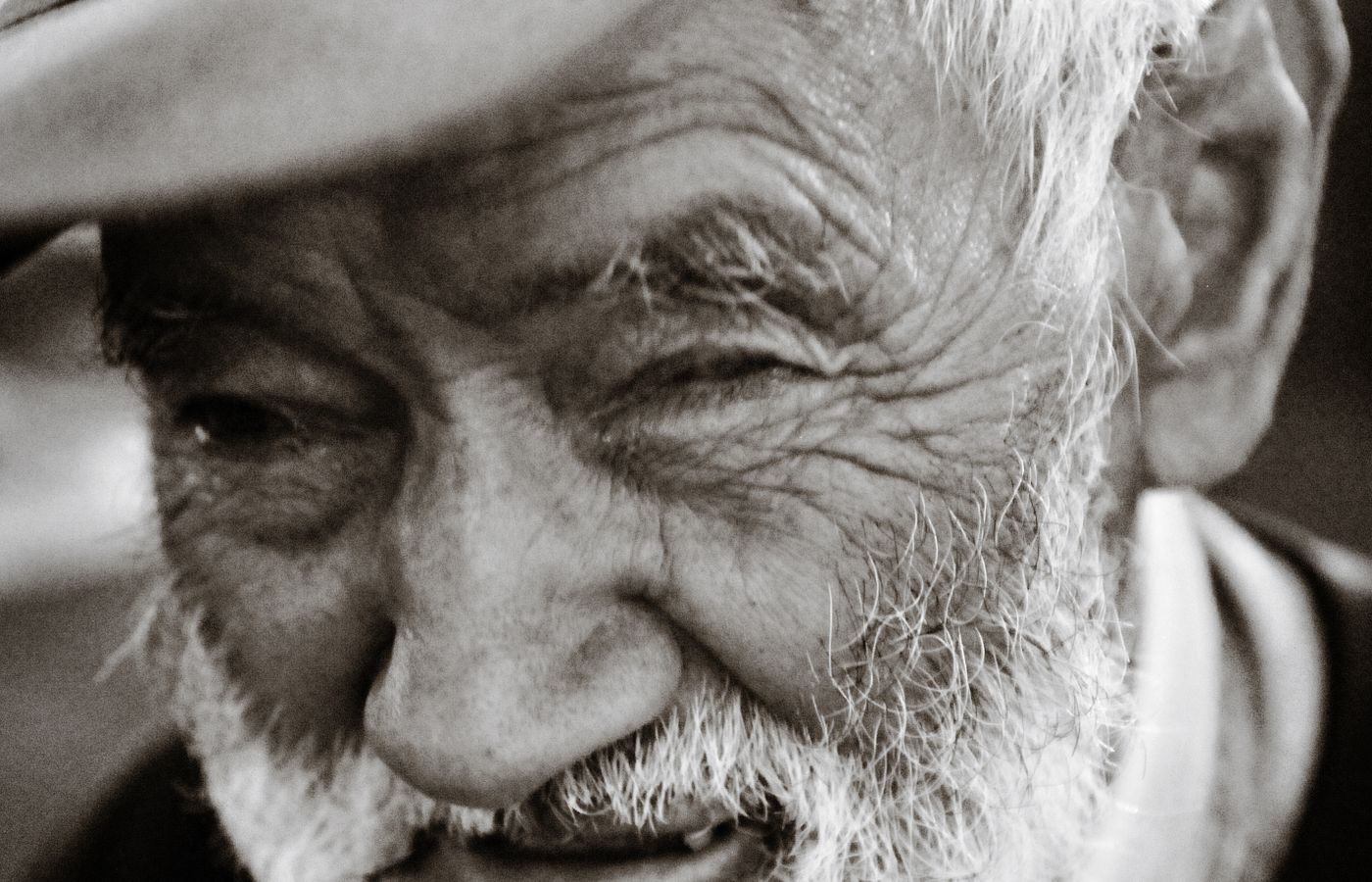 A cheerful older man in a flat cap outdoors