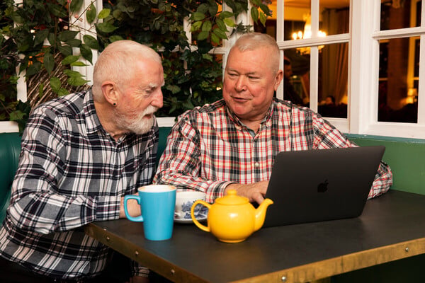 Friends looking at a laptop over cups of tea