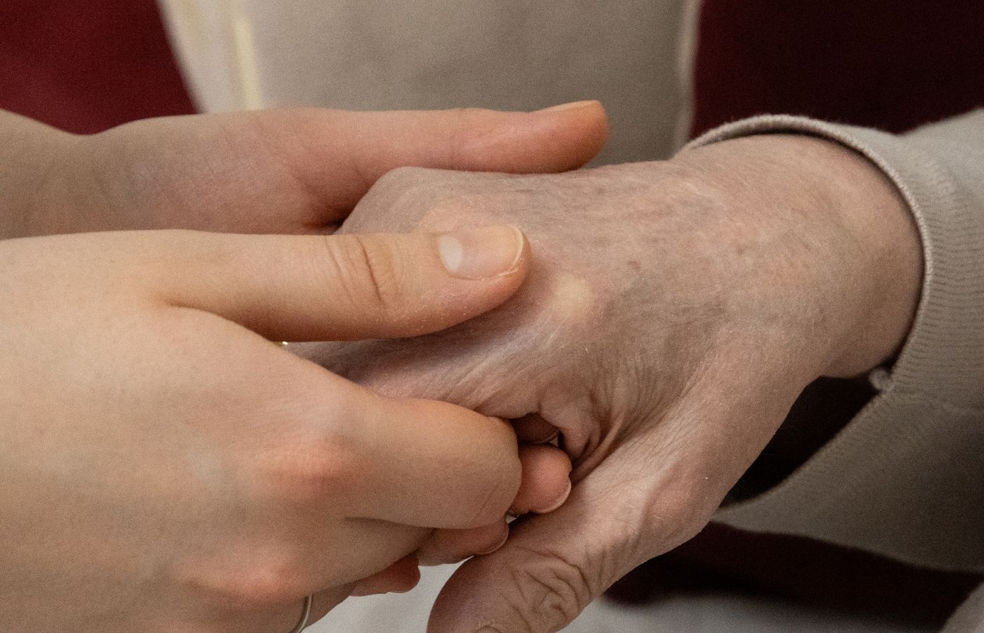 A younger woman leaning close to support an older woman at home