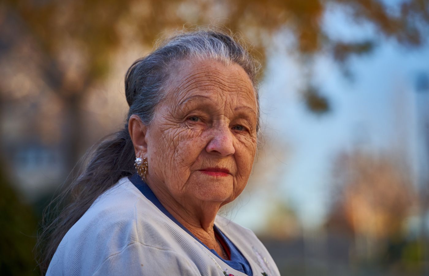 A smiling older woman photographed in warm autumn light