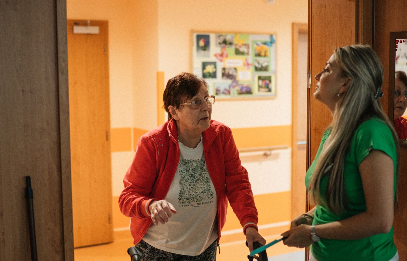 A caregiver helping an older woman with her walker in a doorway