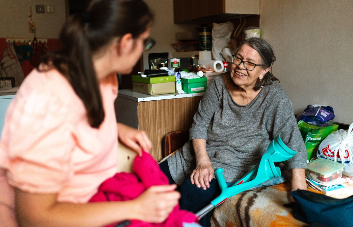 A caregiver helping an older woman sort laundry in her bedroom