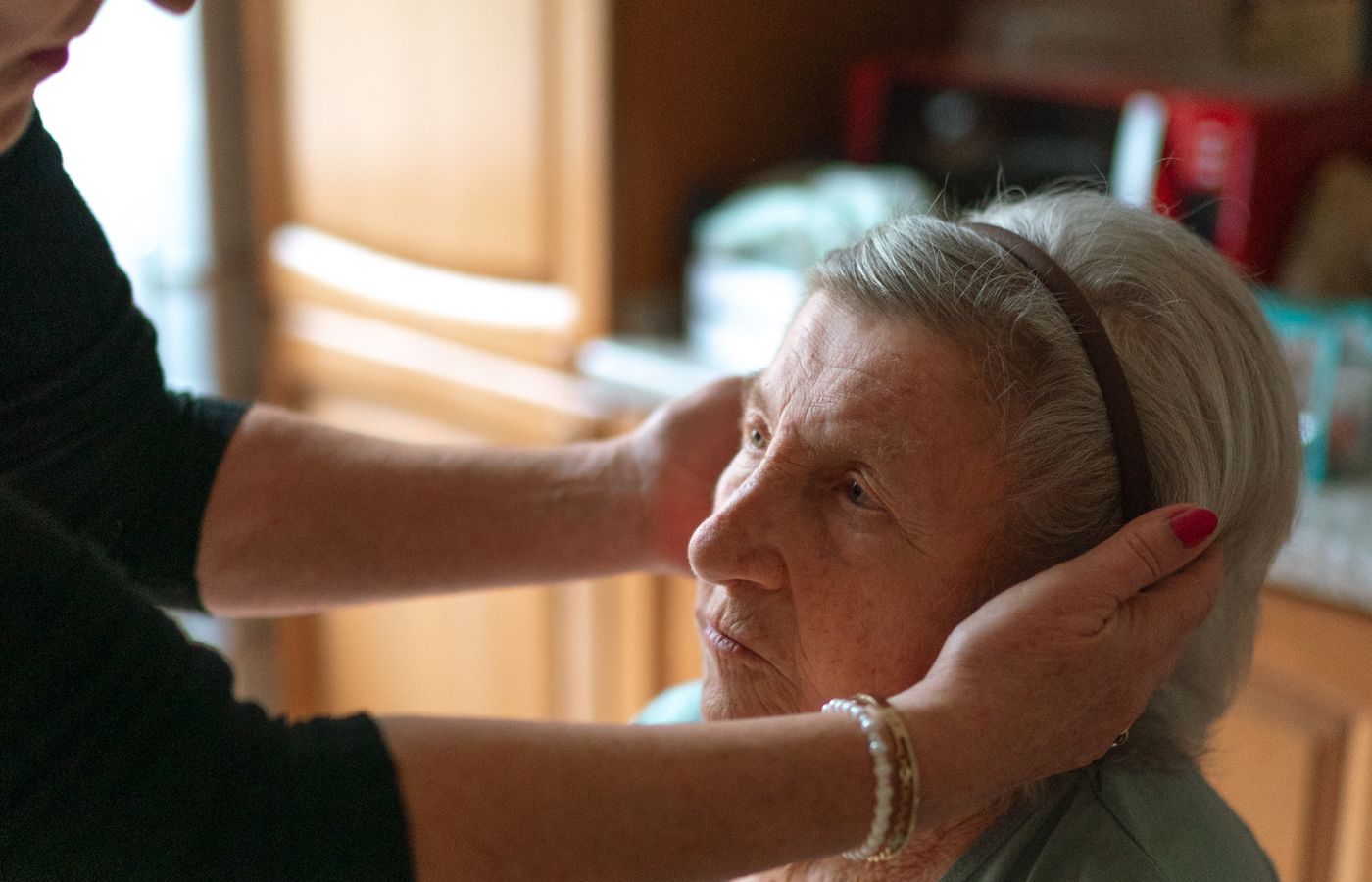 An older woman having her hair gently combed at home